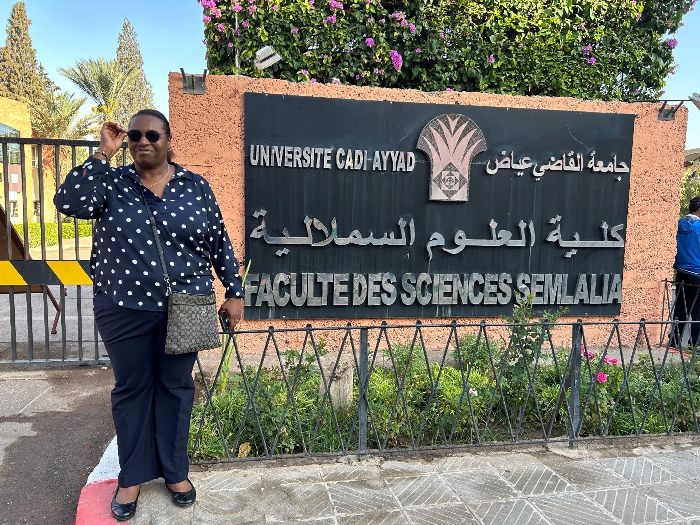 Jacqueline Smith posing in front of Cadi Ayyad University signage